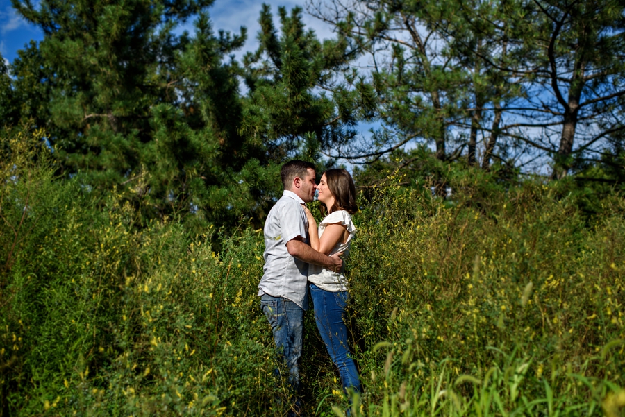 A couple kiss in the tall grass in fishtown.